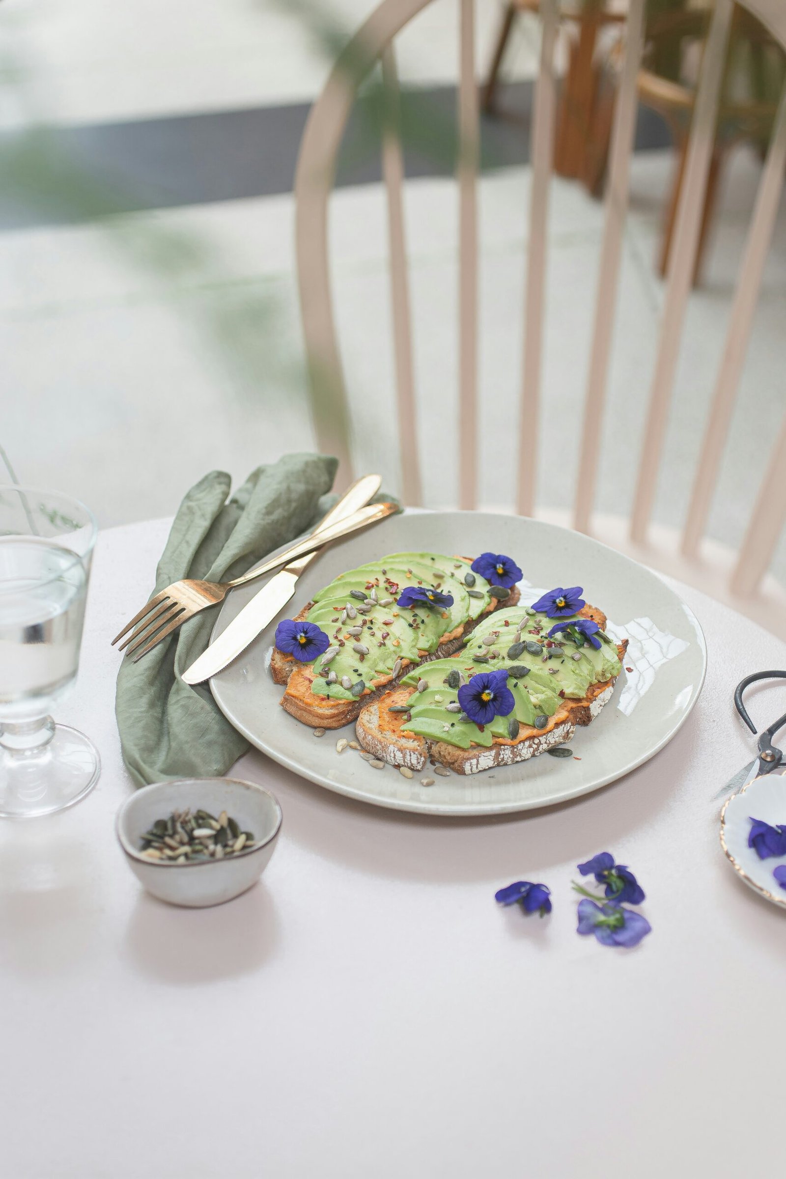 A wooden tray of mixed edible flowers — nasturtium, pansies, calendula, and borage — ready for restaurant delivery